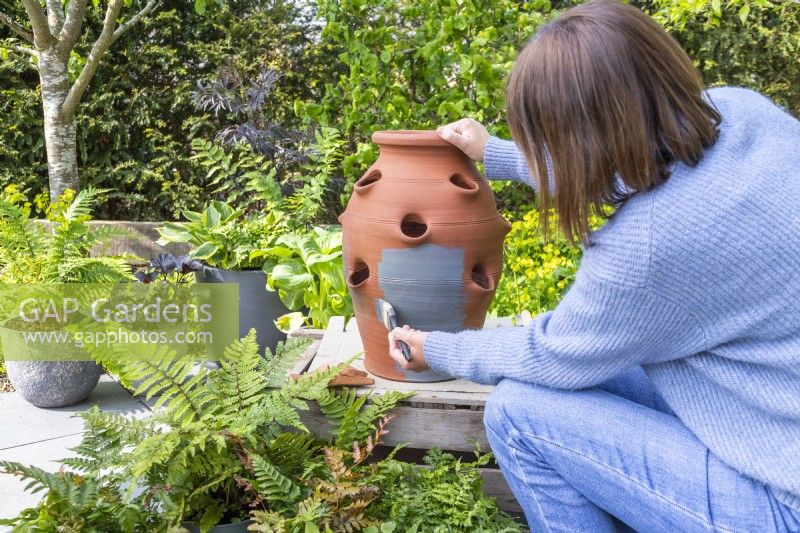 Woman painting the terracotta strawberry planter