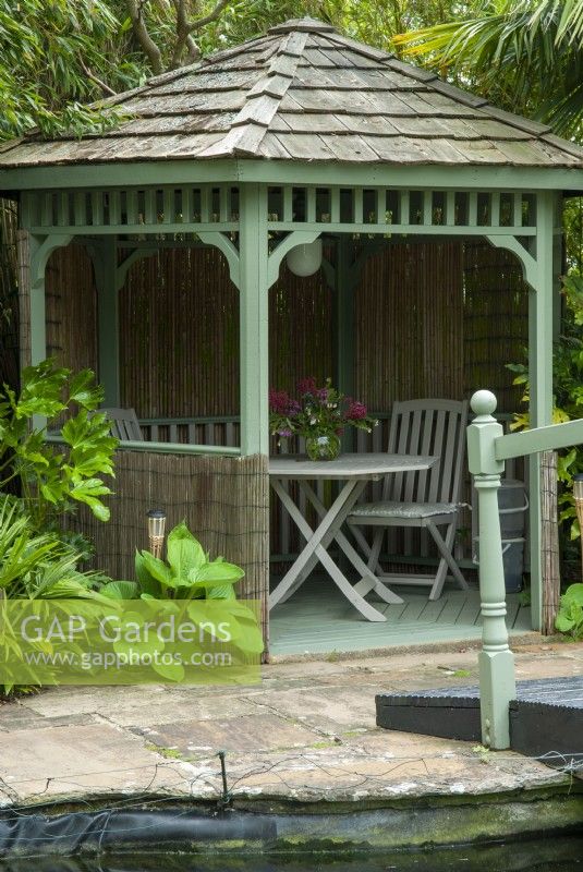 Painted Gazebo in poolside setting with surrounding planting of Bamboo, Hostas and, Fatsia japonica - Open Gardens Day, East Bergholt, Suffolk
