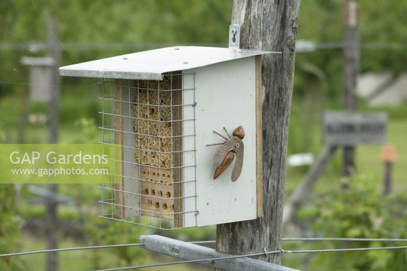 Selfmade bee hotel with wooden and metal bee as decoration.