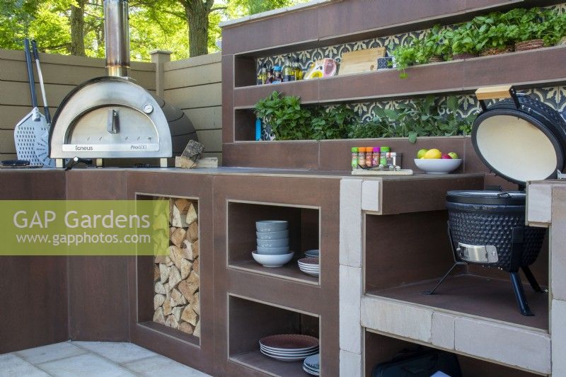 Outdoor kitchen with oven, barbecue, herb plants and storage - The Chic Garden Getaway - BBC Gardeners' World Live 2023 - Designer: Katerina Kantalis
