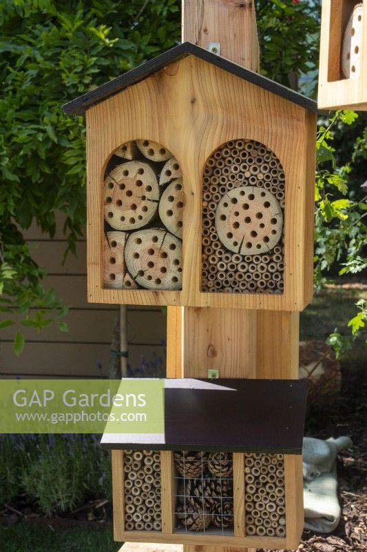 Two wooden garden bug boxes mounted on a post - The Chic Garden Getaway - BBC Gardeners' World Live 2023 - Designer: Katerina Kantalis