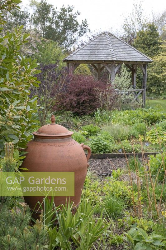 Large terracotta urn in front of wooden summerhouse at Barnsdale Gardens, April