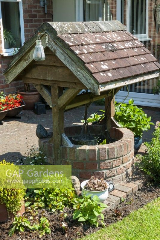 Ornamental well in garden border with surrounding plants - Open Gardens Day, Shelfanger, Norfolk