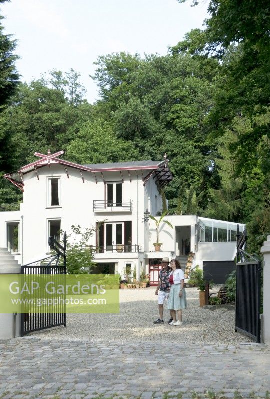 Owners of Villa Sprezzatura welcoming near the black iron gate and villa in the background.
