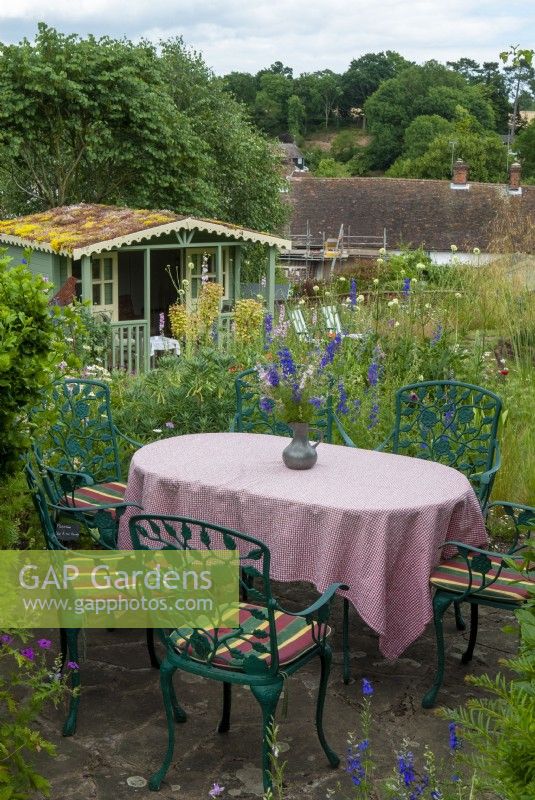 Table with checked tablecloth and chairs for alfresco dining, overlooking lower lawn and summerhouse with living sedum roof - Open Gardens Day, Tuddenham, Suffolk
