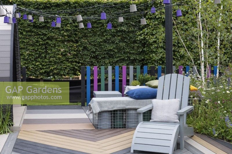 A seating area with rugs and cushions is created on gabions filled with plastic plant pots, a clever way of upcycling waste plastic.