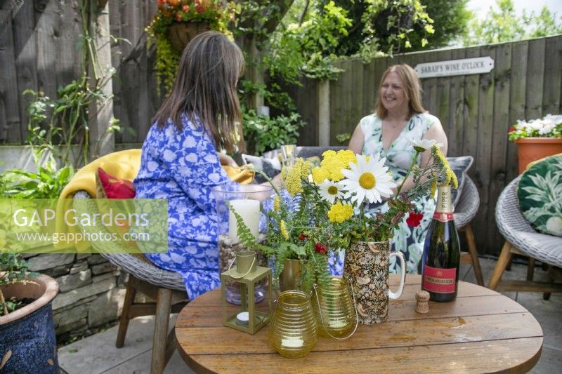 Sarah Hall and friend enjoying wine o'clock in her small suburban garden in Lichfield, Staffordshire, July