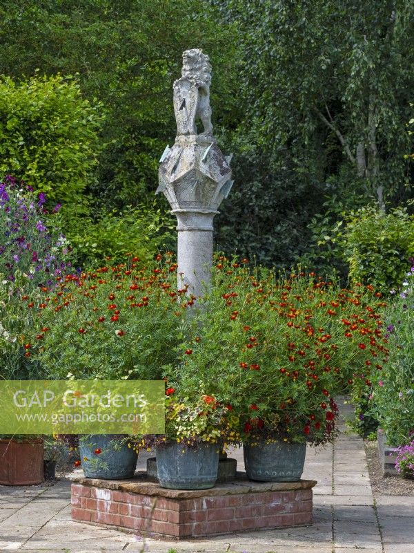 The Scottish Sundial and metal containers with mixed flowers  Old Vicarage Gardens  East Ruston Norfolk July Summer