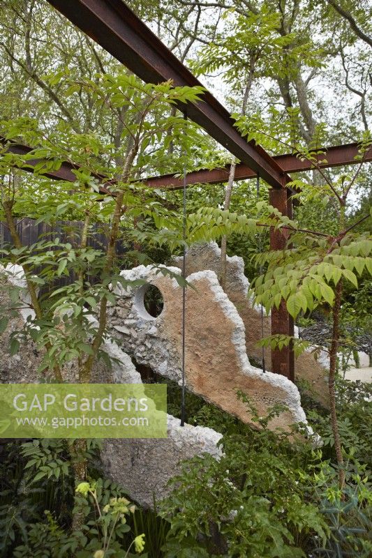 The Samaritans Listening Garden. Designer: Darren Hawkes. Chelsea Flower Show 2023. A garden of salvaged materials. Summer. May. Concrete panel suspended from metal pergola.