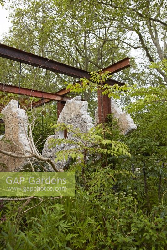 The Samaritans Listening Garden. Designer: Darren Hawkes. Chelsea Flower Show 2023. A garden of salvaged materials. Concrete panels suspended from metal pergola. Summer. May.