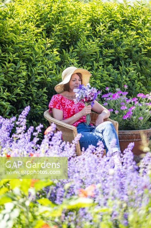 Woman smelling sweet peas while relaxing in garden