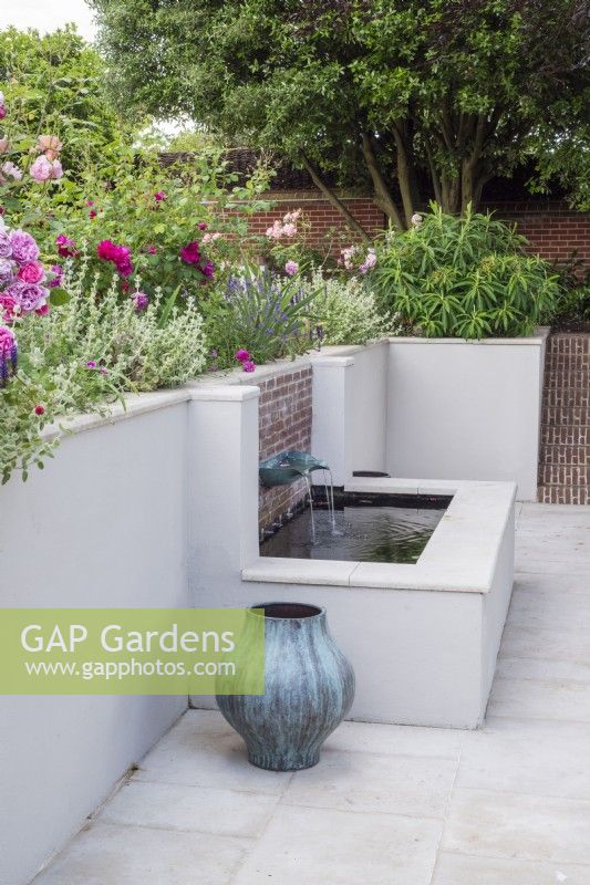 Brick and white rendered raised pool with verdigris fountain basin  incorporated in rendered terrace retaining wall.
