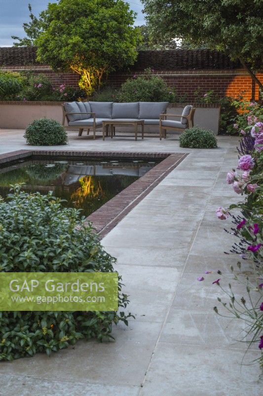 Garden lighting on sandstone terrace with rectangular pool and furniture; and Pittosporum topiary balls for concealed lighting (not showing)