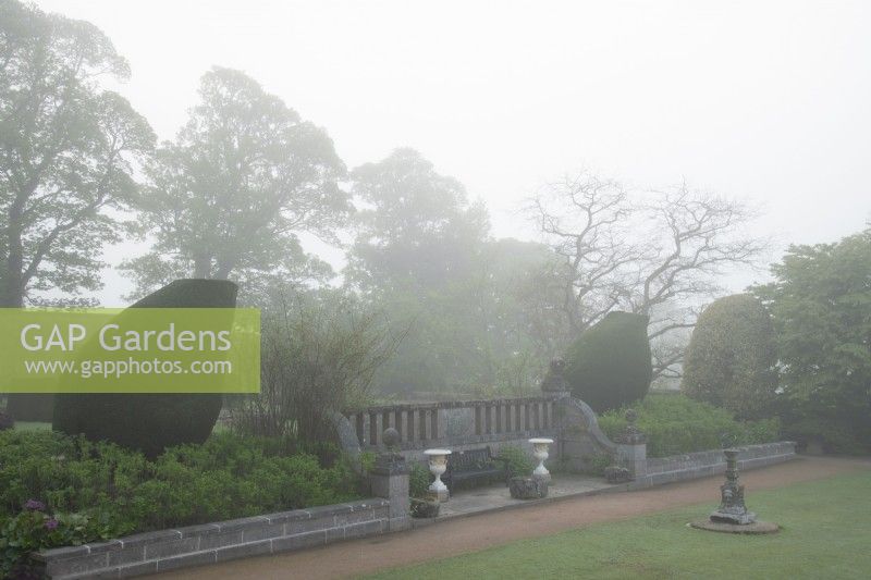 Stonewalls, topiary shapes and urns on a foggy morning at the Croquet Lawn.