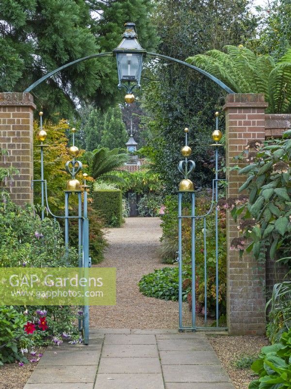 Entrance Court at East Ruston Old Vicarage Gardens, Norfolk. 
 Decorative iron work gateway, walls and paths Autumn  September