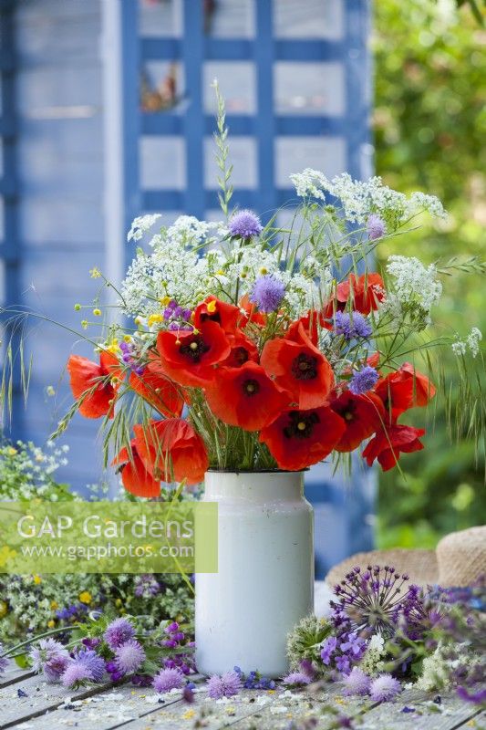 Floral arrangement with poppies and wildflowers in milk can.