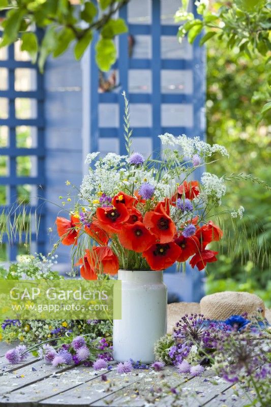 Floral arrangement with poppies and wildflowers in milk can.