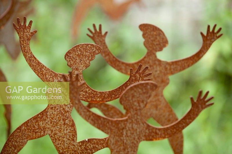 Display of garden ornaments of dancing ladies made from rusting corten steel at Derry Watkins Special Plants Nursery