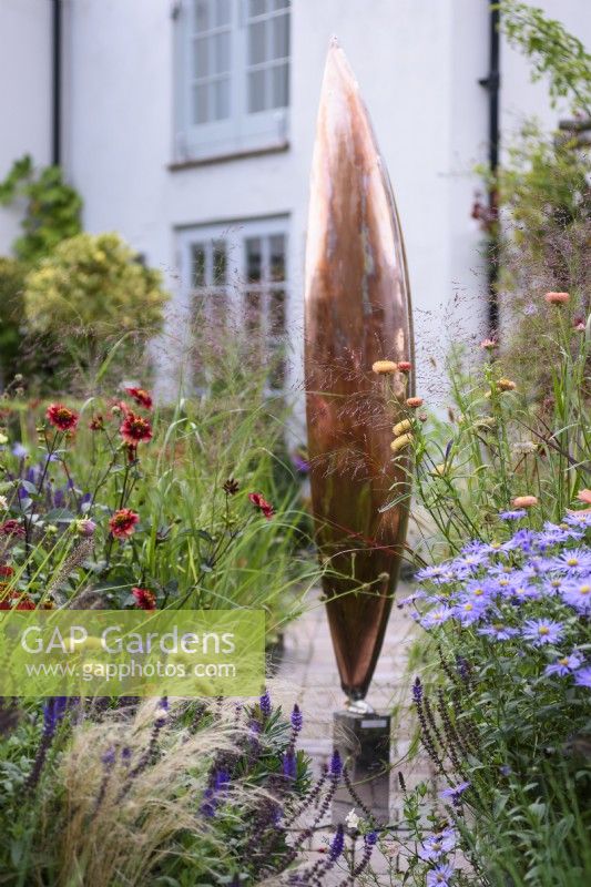 September garden with Seed Pod by Ted Edley surrounded by grasses and herbaceous perennials