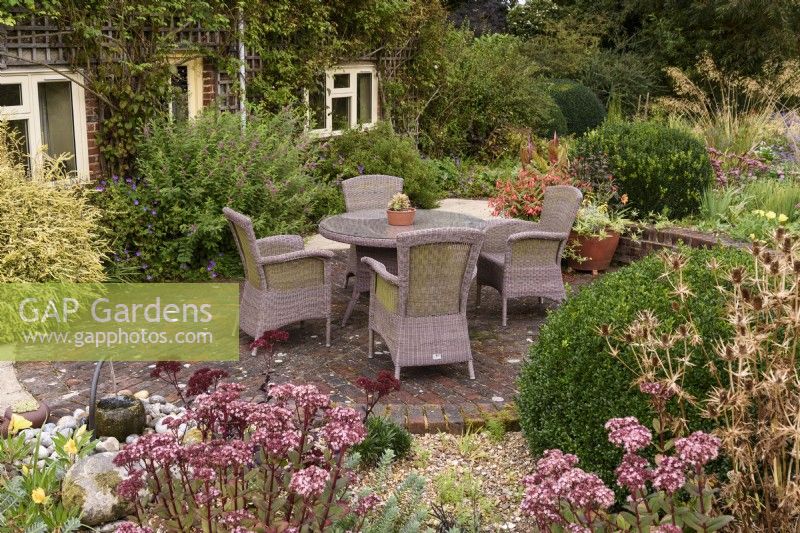 Sunken seating area surrounded by raised borders of sedums and euphorbias in September