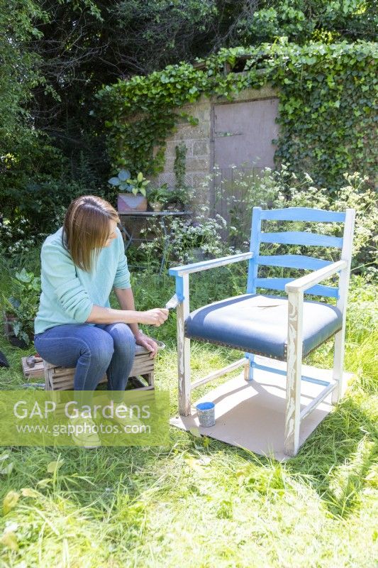 Woman painting the chair blue