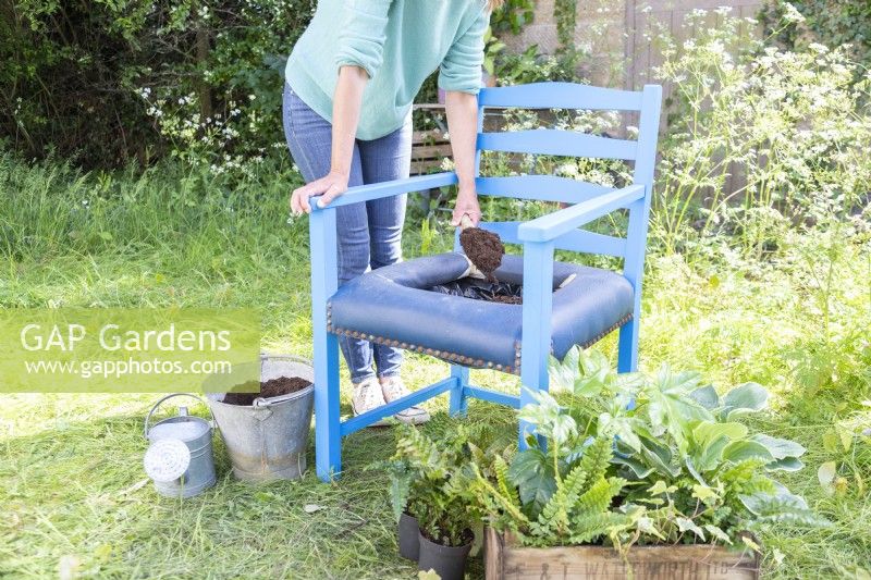 Woman filling chair container with compost