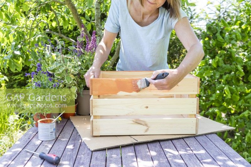Woman painting crate orange