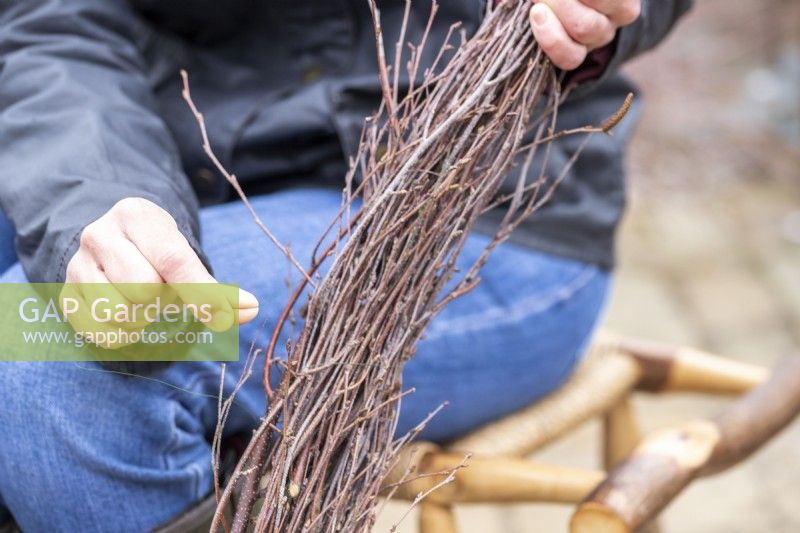 Woman using wire to bind birch twigs together to create a garland