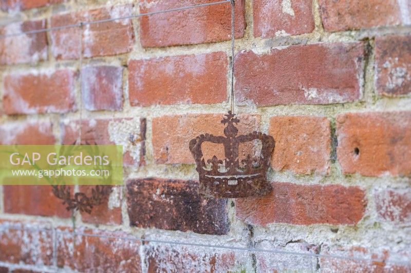 Rusted crown garden ornament hanging against brick wall