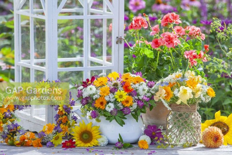 Display of  summer flower wreaths and bouquets made of hydrangea, sunflowers, cosmos, coneflowers, nasturtium, pot marigold, achillea, love in the mist and red clover.
