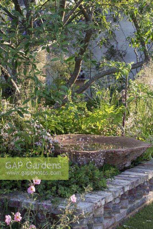 A water bowl handmade from waste material on The Nurture Landscapes Garden designed by Sarah Price with Iris 'Benton Susan' and - RHS Chelsea Flower Show 2023