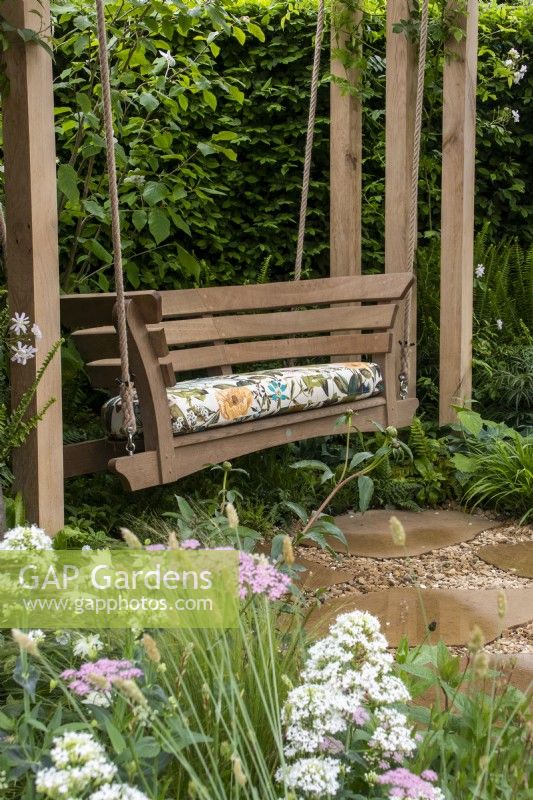 A swing seat enclosed by planting on The London Square Community Garden - Sanctuary Gardens - Designer James Smith - RHS Chelsea Flower Show 2023
