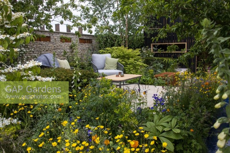 A view across wildlife friendly planting towards a secluded seating area on The RSPCA Garden designed by Martyn Wilson - RHS Chelsea Flower Show 2023