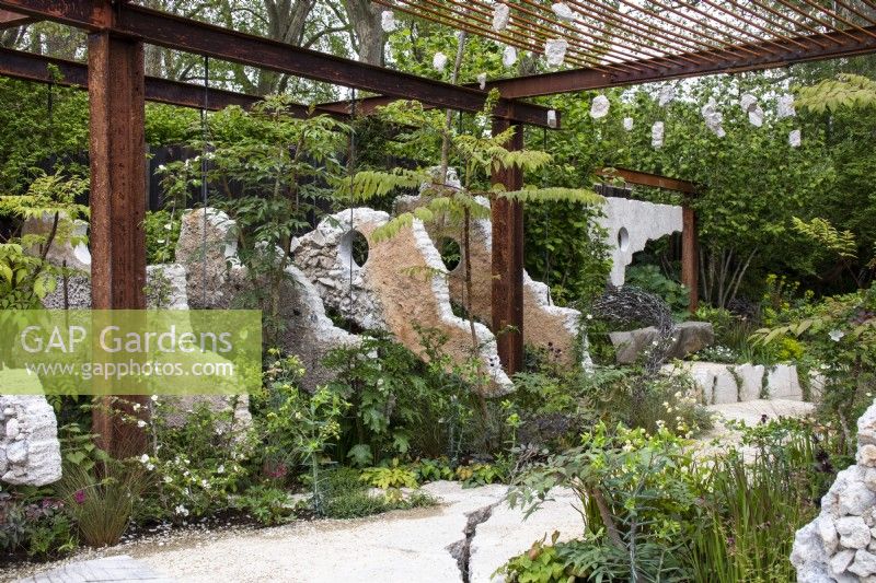 A metal framework and concrete panels amongst planting on the Samaritans' Listening Garden - designer Darren Hawkes - RHS Chelsea Flower Show 2023