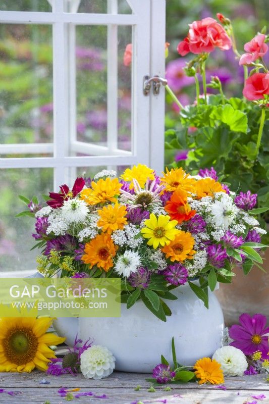 Summer bouquet with pot marigold, coneflowers, love in the mist, cosmos, red clover and achillea in a teapot.