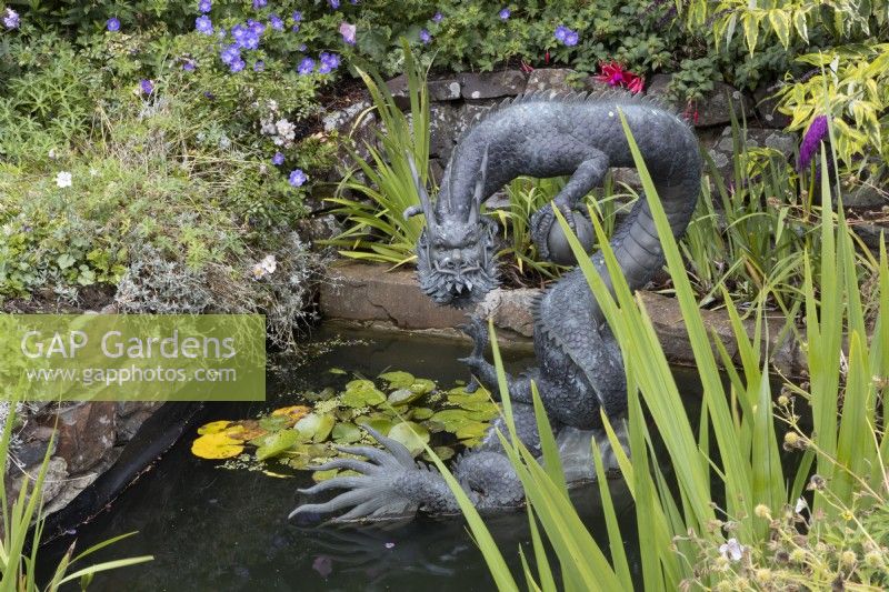 A large copper dragon sculpture, Chinese style, in a pond setting. Summer. 