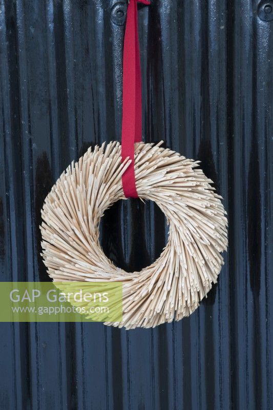 Christmas wreath made from straw and hung using red ribbon