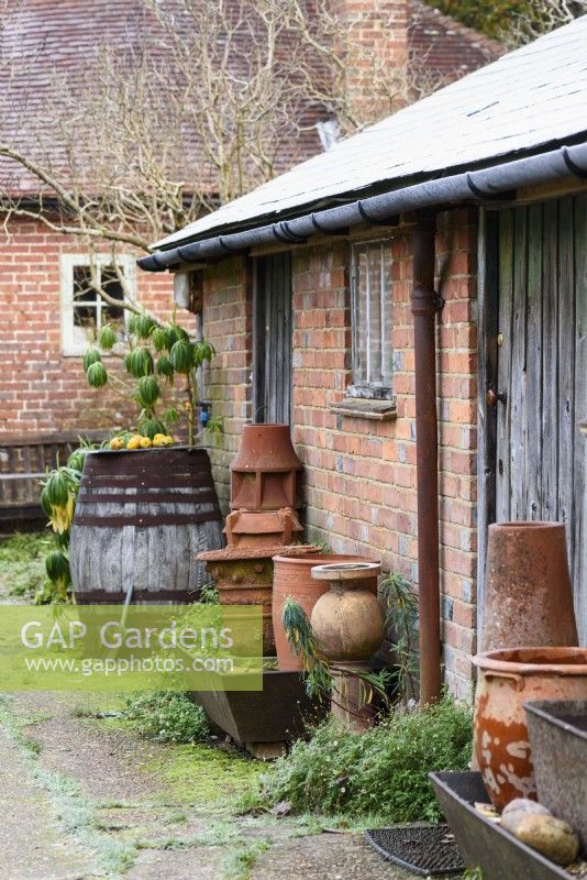 Brick outbuilding with clay pots and containers at Balmoral Cottage, Kent in December