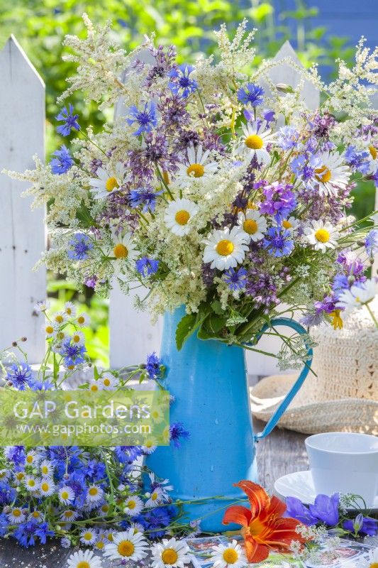 Summer bouquet in a vase containing daisies, cornflowers, wild onions and other wild flowers.