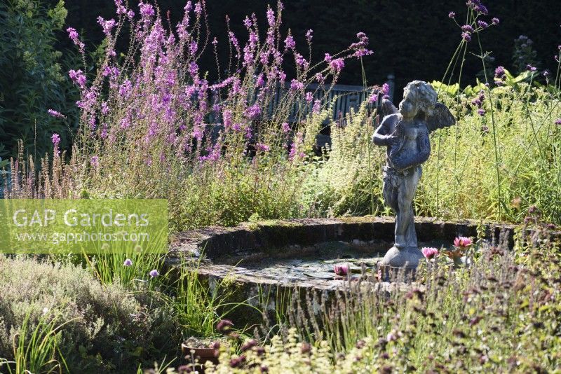 Cherub in a circular pond in the herb garden at Parham House, West Sussex in September