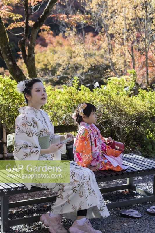 Mother and daughter wearing traditional dress seated in the valley garden. 