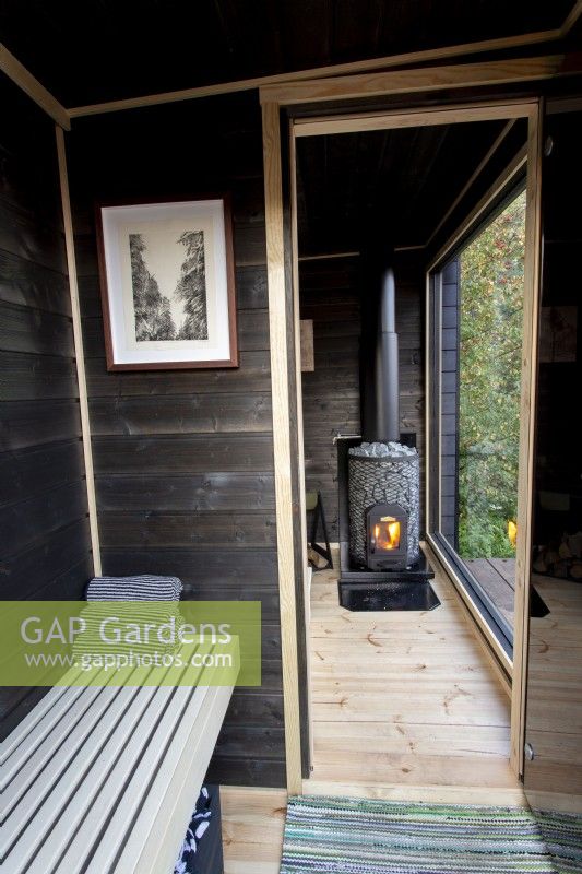 Timber black painted wood sauna cabin with a glass window view to the garden