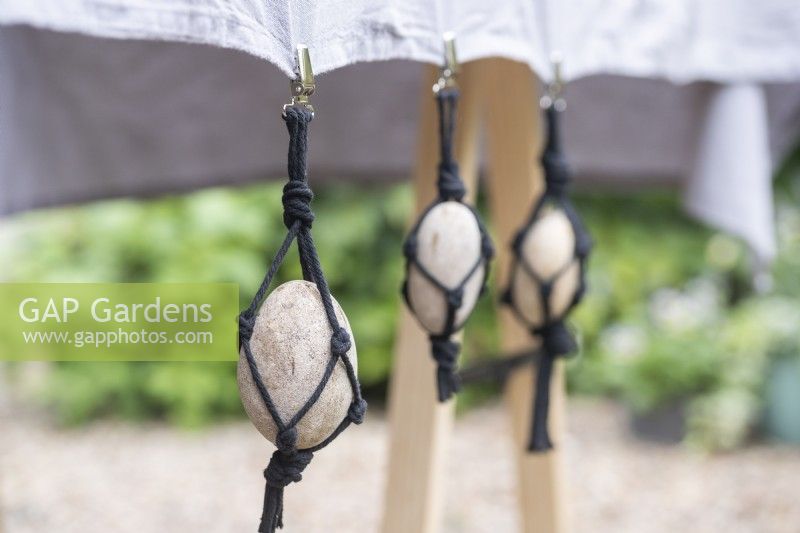 Large pebbles in black string net hanging from table cloth