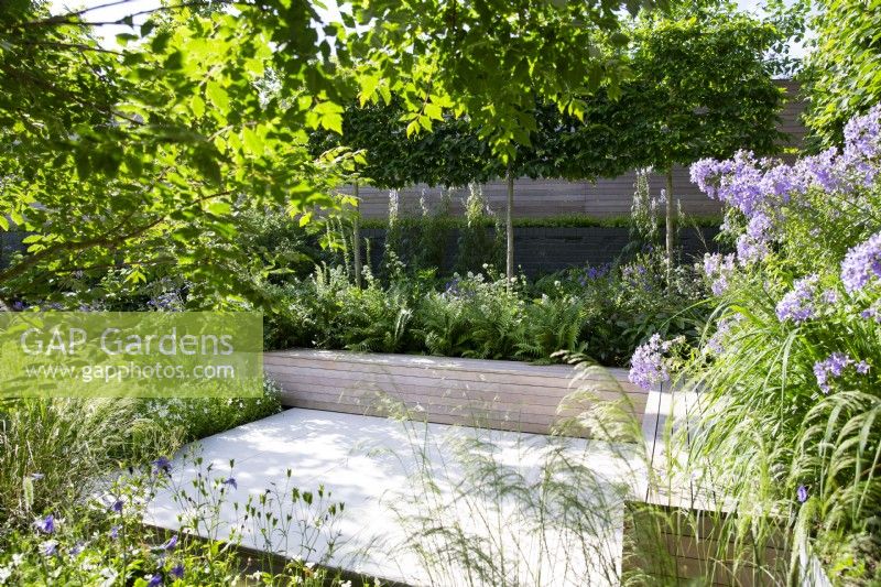Sheltered seating area in modern garden with lush planting and built-in bench seating