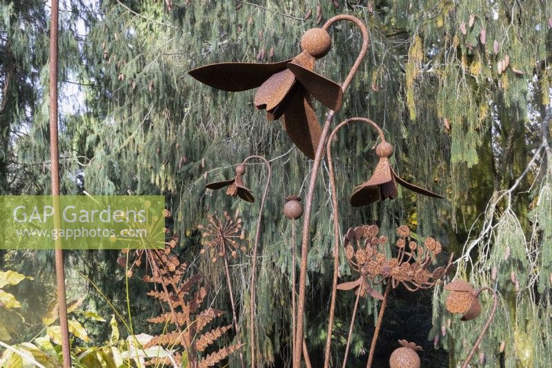Several rusty, metal garden sculptures of flowers and leaves including snowdrops and ferns. The Garden House, Yelverton. Autumn, November