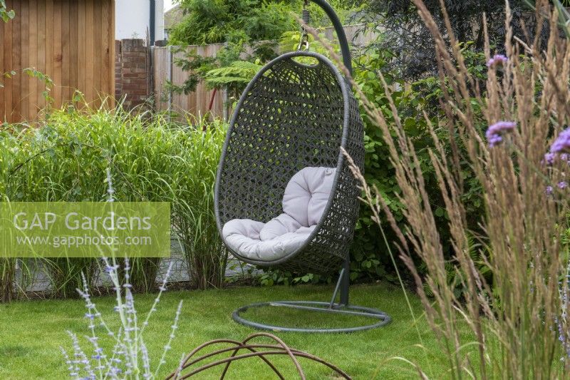 A corner of a lawn provides a cool, sheltered spot for a swing chair.