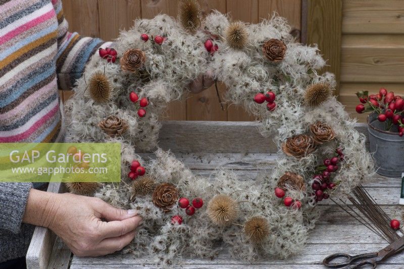 Step-by-Step making a Countryside Wreath from a wire frame wrapped in old man's beard. Step 8: the completed wreath, with the hips, teasels, berries and cones secured onto the metal frame with florists' wire.