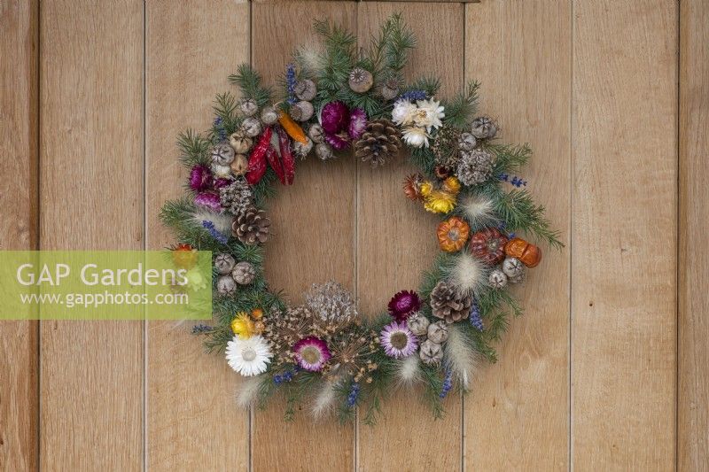 A Gardener's Garland wreath, made from a woven willow frame 
covered in spruce foliage, and decorated with dried flowers, cones, wired seedheads and fruits.