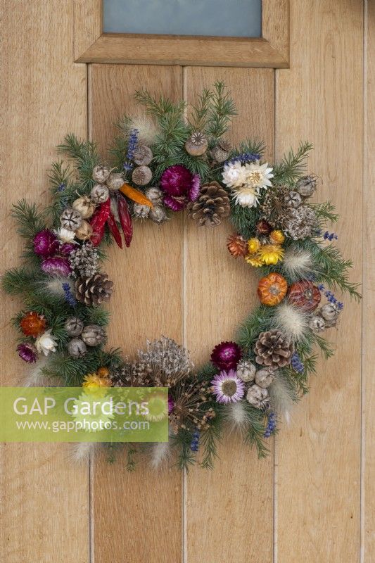 A Gardener's Garland wreath, made from a woven willow frame 
covered in spruce foliage, and decorated with dried flowers, cones, wired seedheads and fruits.