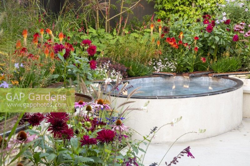 Modern copper metal rills with water flowing into a raised small pool - mixed perennial planting of Echinacea purpurea 'Magnus', Dahlia 'Black Narcissus', Kniphofia 'Papaya Popsicle'